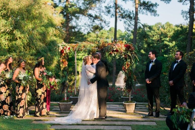 Bride and Groom say i do and have their first kiss under burgundy floral arbor by Meristem Floral in Raleigh at The Umstead, Connection