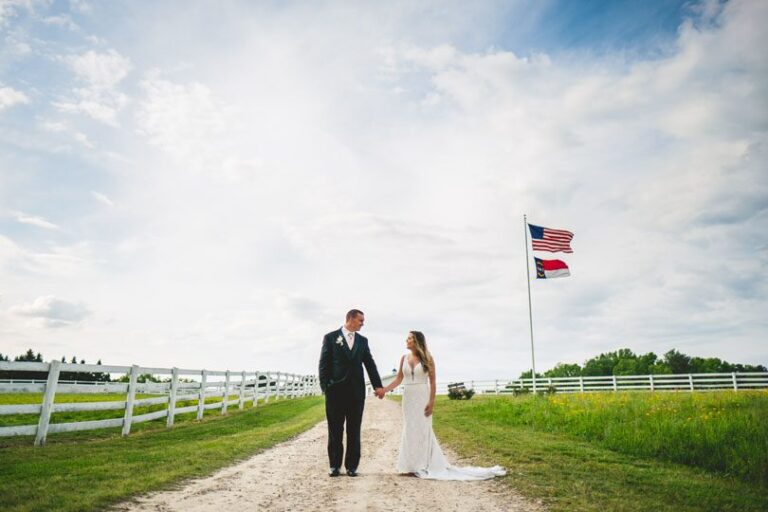 Bride and groom in grass field with american and north carolina flag at Bennett Bunn Plantation, Rob and Kristen