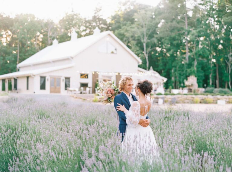 The bride and groom embrace in a field of lavender at Lavender Oaks Farm. Photo by Arika Jordan Photography.